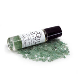 Heart Chakra roller bottle laying on crushed green aventurine crystals. Soul Ritual chakra roller bottle collection for heart chakra infused with reiki, green aventurine crystals, and chakra essential oil blend for your energetic well-being,
