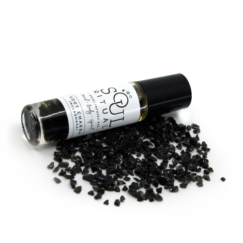 Root Chakra roller bottle laying on crushed black obsidian gemstones. Soul Ritual chakra roller bottle collection for root chakra infused with reiki, black obsidian and chakra essential oil blend for your energetic well-being,