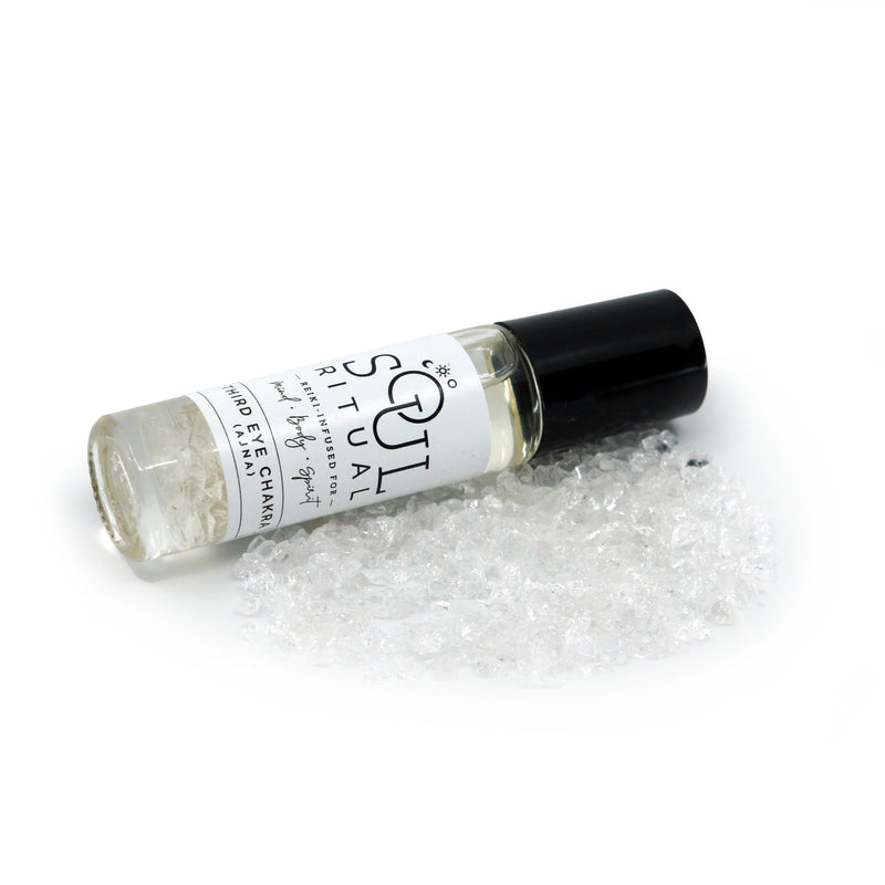  Third Eye Chakra roller bottle laying on crushed clear quartz crystals. Soul Ritual chakra roller bottle collection for Third Eye chakra infused with reiki, clear quartz and chakra essential oil blend for your energetic well-being.